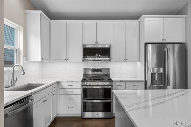 Kitchen featuring stainless steel appliances, a sink, light stone counters, and decorative backsplash | Image 8