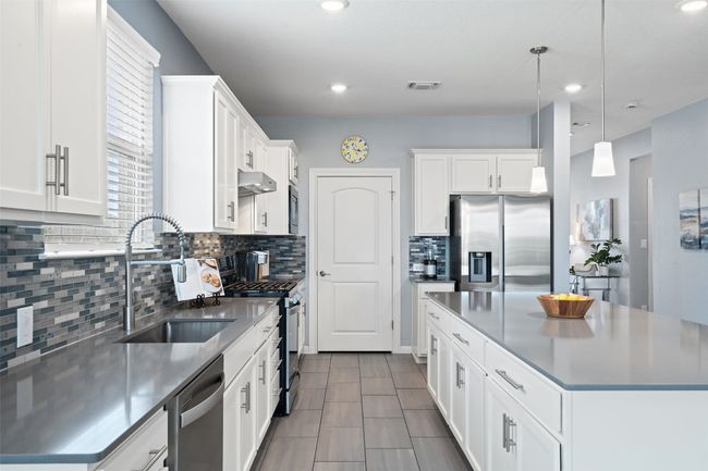 The stunning kitchen includes quartz countertops, spacious pantry, SS appliances, and an abundance of cabinetry. | Image 10