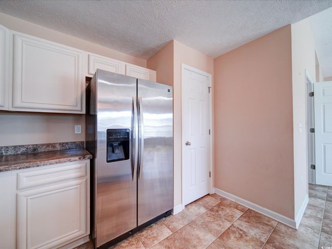 Kitchen with stainless steel fridge with ice dispenser, white cabinetry, and a textured ceiling | Image 18