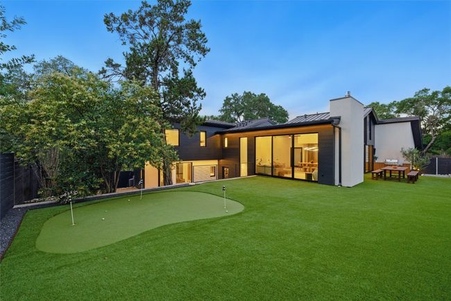 Rear view of house featuring an area to practice putting, a standing seam roof, a fenced backyard, and metal roof | Image 7