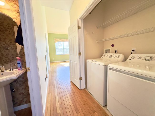 Washroom featuring laundry area, baseboards, light wood finished floors, and separate washer and dryer | Image 6