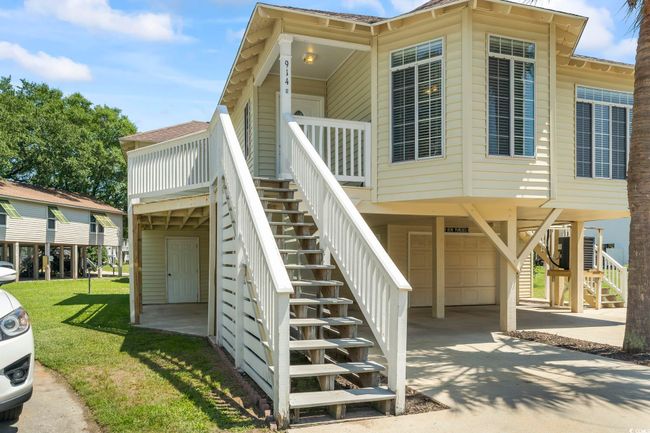 View of property exterior with stairs, a carport, an attached garage, concrete driveway, and a yard | Image 5