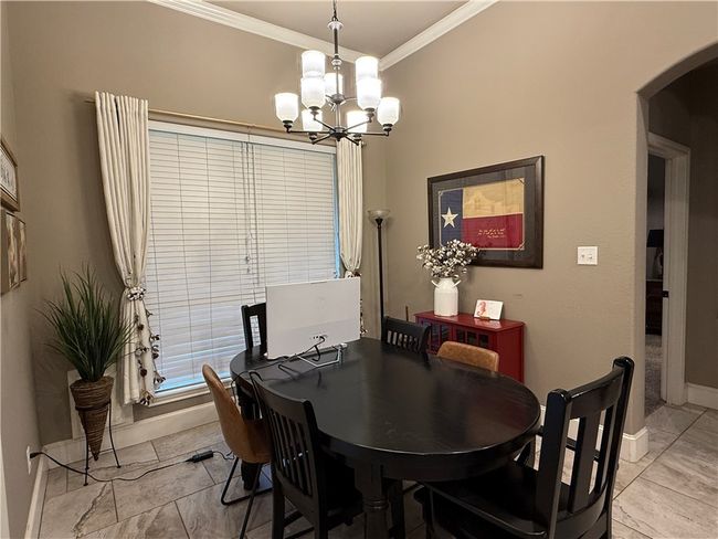 Dining space featuring a chandelier, arched walkways, crown molding, and light tile patterned flooring | Image 10
