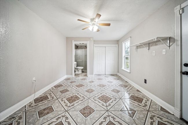Unfurnished bedroom featuring light tile patterned flooring, a closet, a ceiling fan, and ensuite bathroom | Image 14