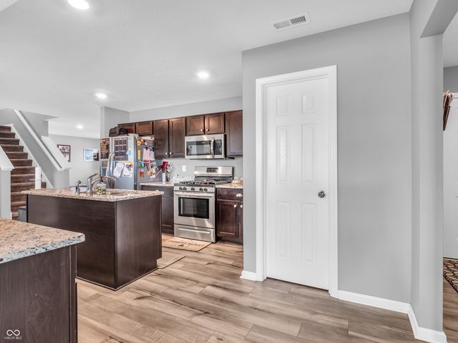 kitchen featuring appliances with stainless steel finishes, visible vents, dark brown cabinets, recessed lighting, and a center island with sink | Image 10