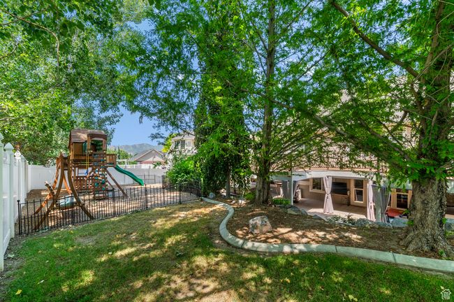 Fenced backyard featuring a playground and a patio | Image 45