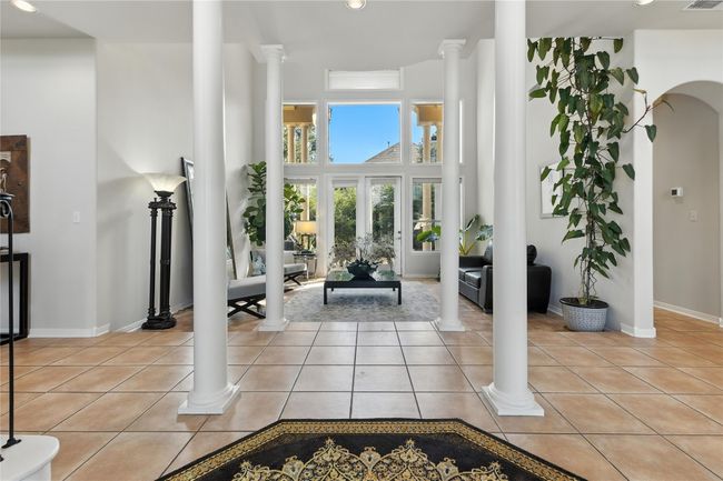 Entryway featuring light tile patterned floors, decorative columns, a towering ceiling, arched walkways, and recessed lighting | Image 9