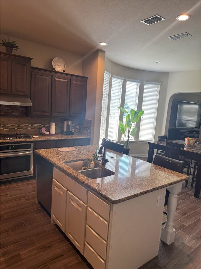 Kitchen with appliances with stainless steel finishes, under cabinet range hood, dark wood-type flooring, recessed lighting, and backsplash | Image 18