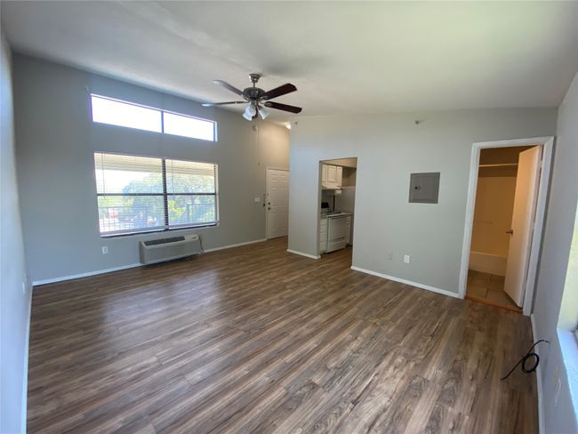 This living area contains beautiful new flooring. Notice the large window and the lighted ceiling fan. | Image 4