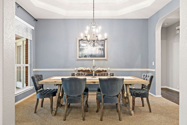 Dining space featuring a chandelier, carpet floors, a raised ceiling, arched walkways, and crown molding | Image 6