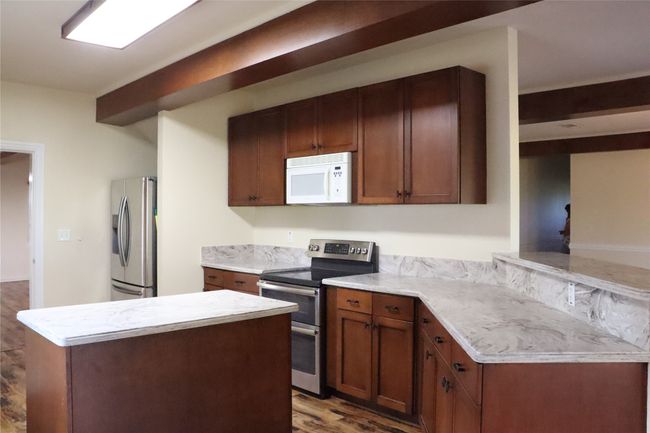 Kitchen with a center island, wood finished floors, stainless steel appliances, and light countertops | Image 8