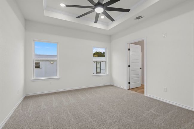 Carpeted spare room featuring crown molding, ceiling fan, and a raised ceiling | Image 22