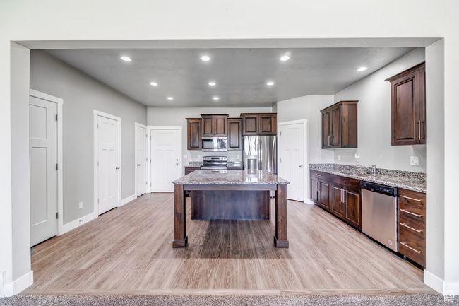 Kitchen featuring appliances with stainless steel finishes, dark brown cabinetry, and light wood-style flooring | Image 5