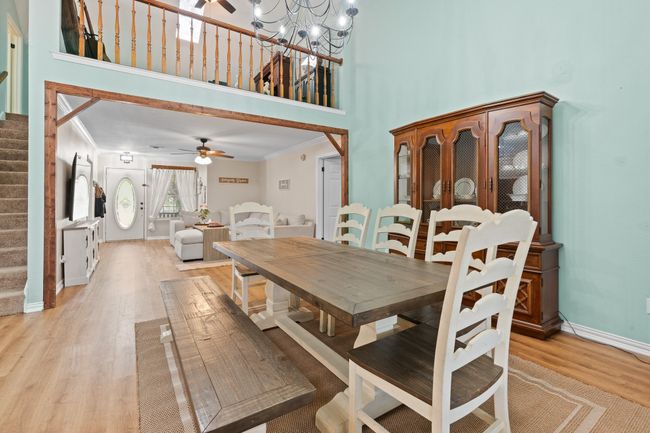 Dining room featuring stairs, a ceiling fan, light wood-style flooring, crown molding, and a high ceiling | Image 11