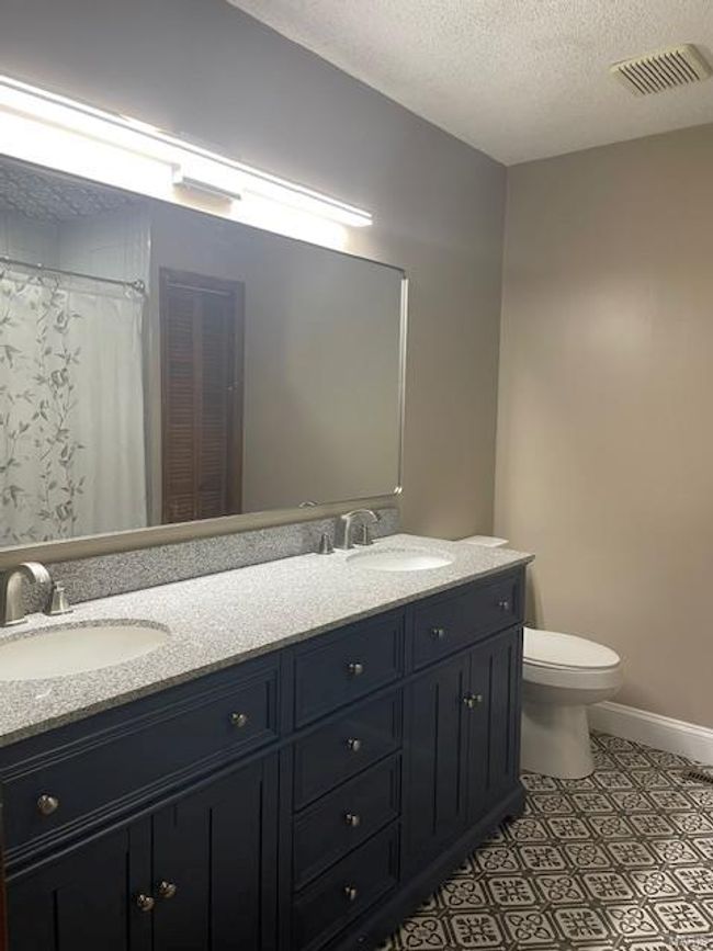 Bathroom featuring vanity, tile patterned flooring, toilet, and a textured ceiling | Image 17