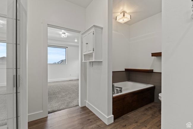 Bathroom with a bath, wood finished floors, toilet, and baseboards | Image 20
