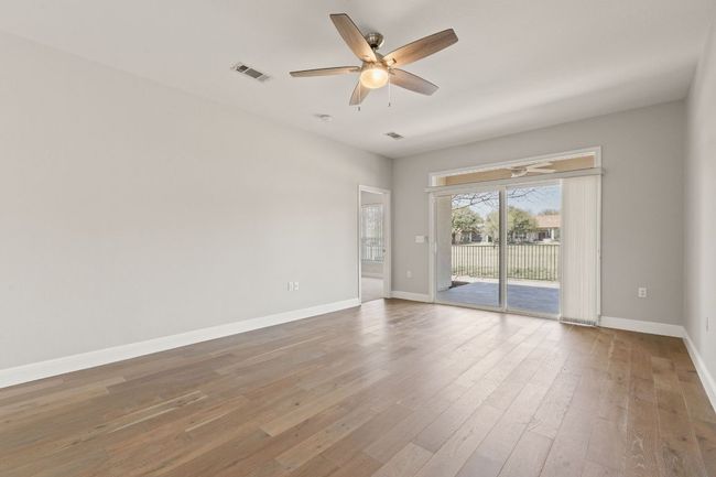 Empty room with baseboards, visible vents, wood finished floors, and ceiling fan | Image 14