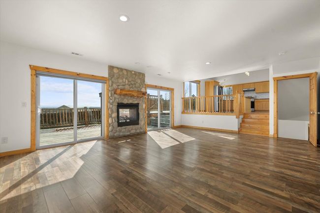 Unfurnished living room featuring wood finished floors, baseboards, a fireplace, recessed lighting, and stairway | Image 5