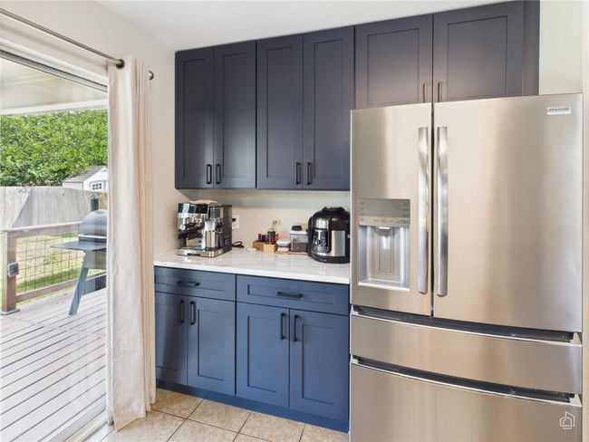 Kitchen featuring stainless steel refrigerator with ice dispenser, light countertops, and light tile patterned floors | Image 10