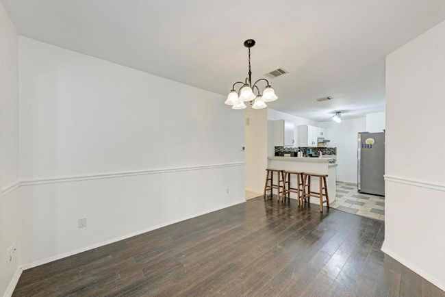 Dining area featuring dark wood-type flooring, a notable chandelier, baseboards, and visible vents | Image 11