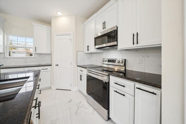Kitchen featuring white cabinets, appliances with stainless steel finishes, and tasteful backsplash | Image 7