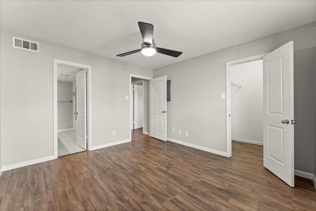 Unfurnished bedroom featuring a spacious closet, wood finished floors, a ceiling fan, and connected bathroom | Image 24