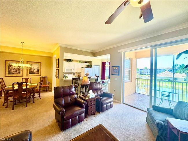 Living room with light carpet, a textured ceiling, ornamental molding, and ceiling fan with notable chandelier | Image 15