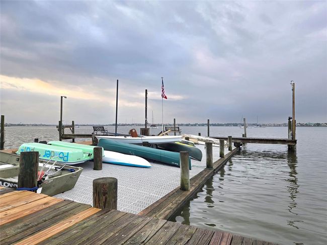 This photo showcases a tranquil waterfront view with a dock equipped for boats and kayaks, offering serene water access and picturesque skies, ideal for water enthusiasts. | Image 26