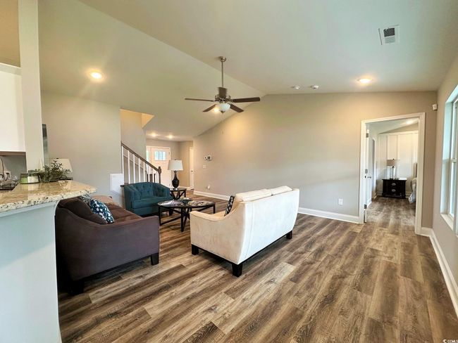 Living area with visible vents, baseboards, dark wood-style flooring, ceiling fan, and lofted ceiling | Image 5