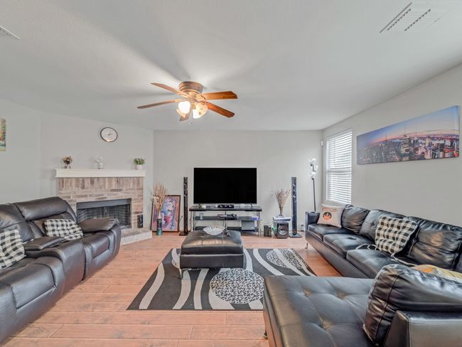 Living room featuring a ceiling fan, light wood-type flooring, and a fireplace | Image 5