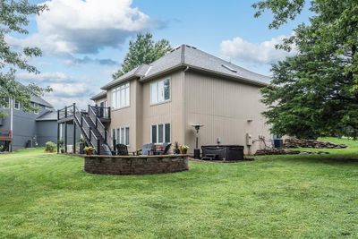 Back of property featuring a hot tub, a wooden deck, a patio area, cooling unit, and a lawn | Image 3