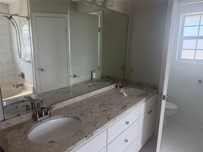 Bathroom with toilet, double vanity, tub / shower combination, baseboards, and tile patterned floors | Image 6