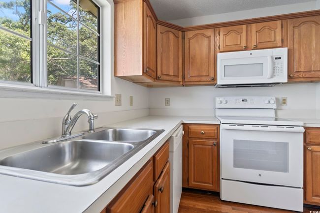 Kitchen featuring white appliances, a sink, brown cabinetry, and light countertops | Image 16