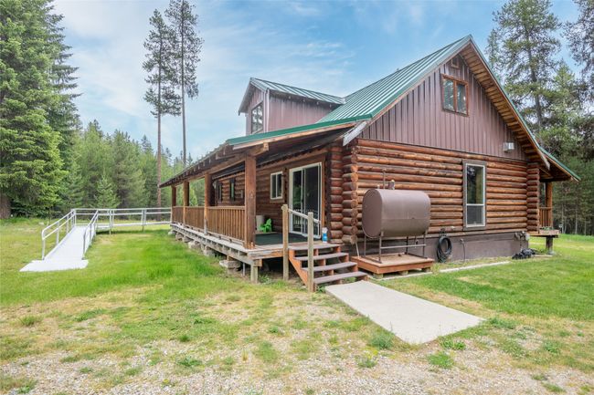 Back of property featuring heating fuel, a lawn, log exterior, board and batten siding, and a wooden deck | Image 24