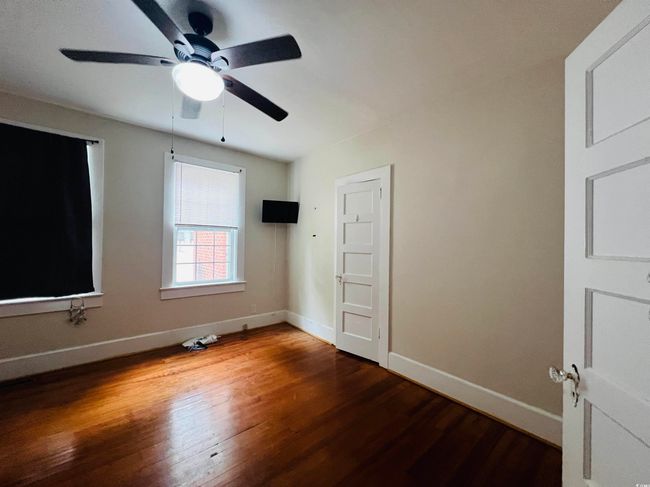 Unfurnished bedroom featuring wood finished floors, a ceiling fan, and baseboards | Image 9