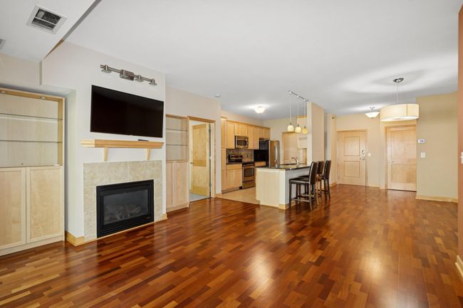 The living room, kitchen, & dining area feature an open-concept design that fosters a warm, inviting atmosphere—perfect for both everyday living & entertaining. Rich maple millwork is a standout feature throughout the home, adding warmth & character! | Image 4