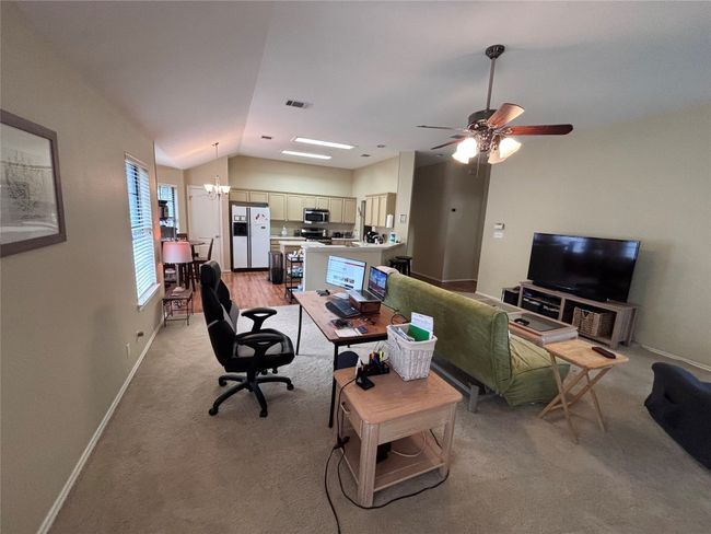 Living area featuring lofted ceiling, a chandelier, light carpet, and a ceiling fan | Image 4