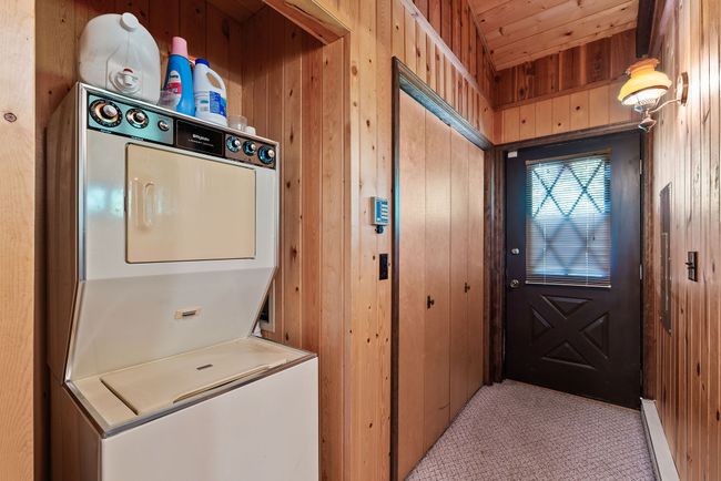 Entry way featuring stacked washer and dryer, wood walls, light colored carpet, and wooden ceiling | Image 10