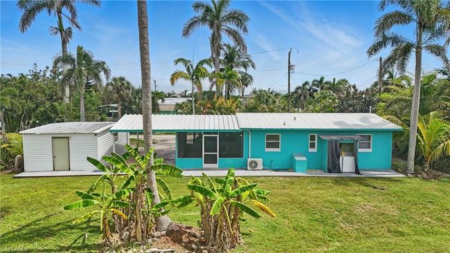 Rear view of property featuring a sunroom, a yard, a metal roof, and a shed | Image 37