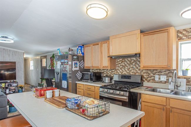 Kitchen featuring light brown cabinets, crown molding, sink, and appliances with stainless steel finishes | Image 6