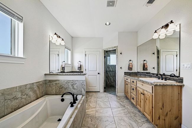 Full bathroom with vanity, a bath, a stall shower, and marble look tiles | Image 19