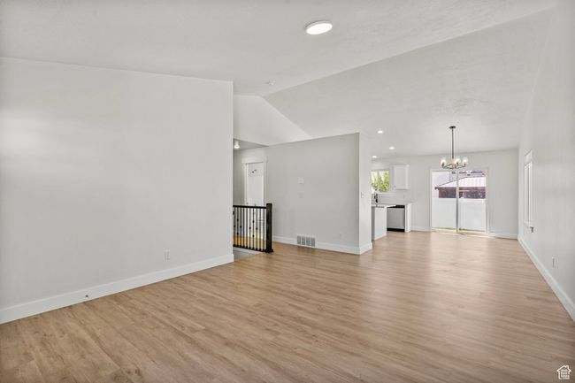 Unfurnished living room featuring a chandelier, lofted ceiling, and light wood-style flooring | Image 10