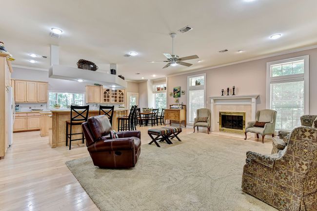 Living area featuring a tile fireplace, plenty of natural light, visible vents, and crown molding | Image 9