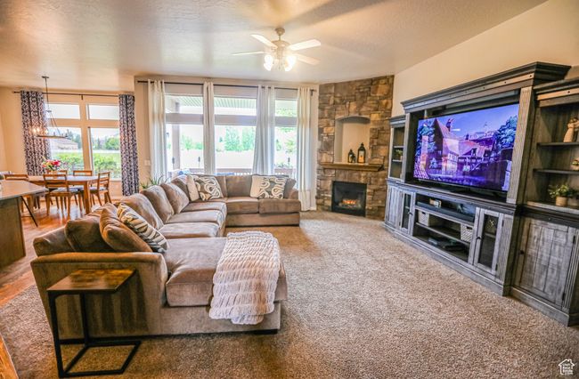 Carpeted living room featuring ceiling fan, a fireplace, and a chandelier | Image 5