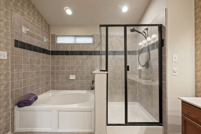 Spa-like primary bath with garden soaking tub, walk-in shower, double sinks, and tile flooring. | Image 25