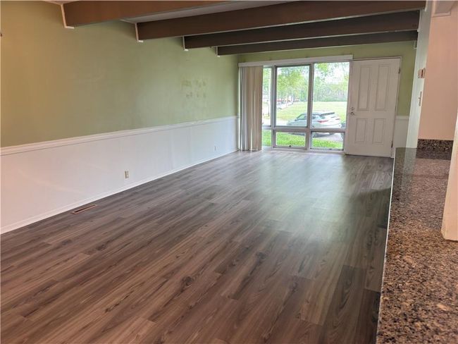 Unfurnished room featuring beam ceiling, dark wood-type flooring, and a wainscoted wall | Image 5