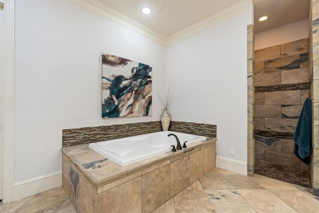 Wash away the stress of the day in this extra-large, soaker tub with tile surround. Doors just out of view lead to a water closet, linen storage, and to the walk-in closet. | Image 29