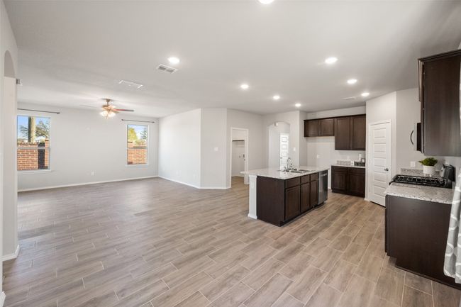 Kitchen featuring a sink, arched walkways, visible vents, a ceiling fan, and dark brown cabinets | Image 28