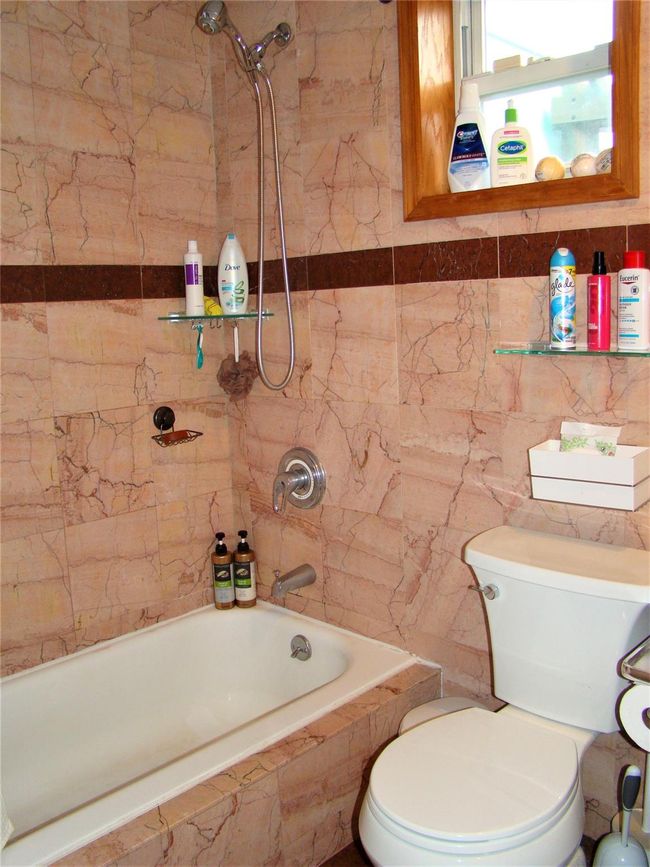 Bathroom featuring tiled shower / bath, toilet, and tile walls | Image 24