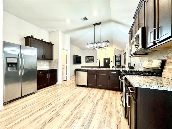 Full view of spacious kitchen with ample natural light, cabinets, counter tops, and lots of upgrades such as lighting, sink, and luxurious gas stove. | Image 8